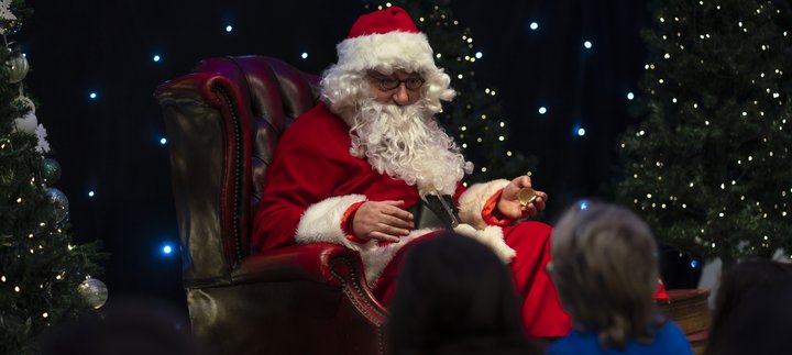 Children sat in front of a seating Santa as he reads to them at Woodhorn Museum