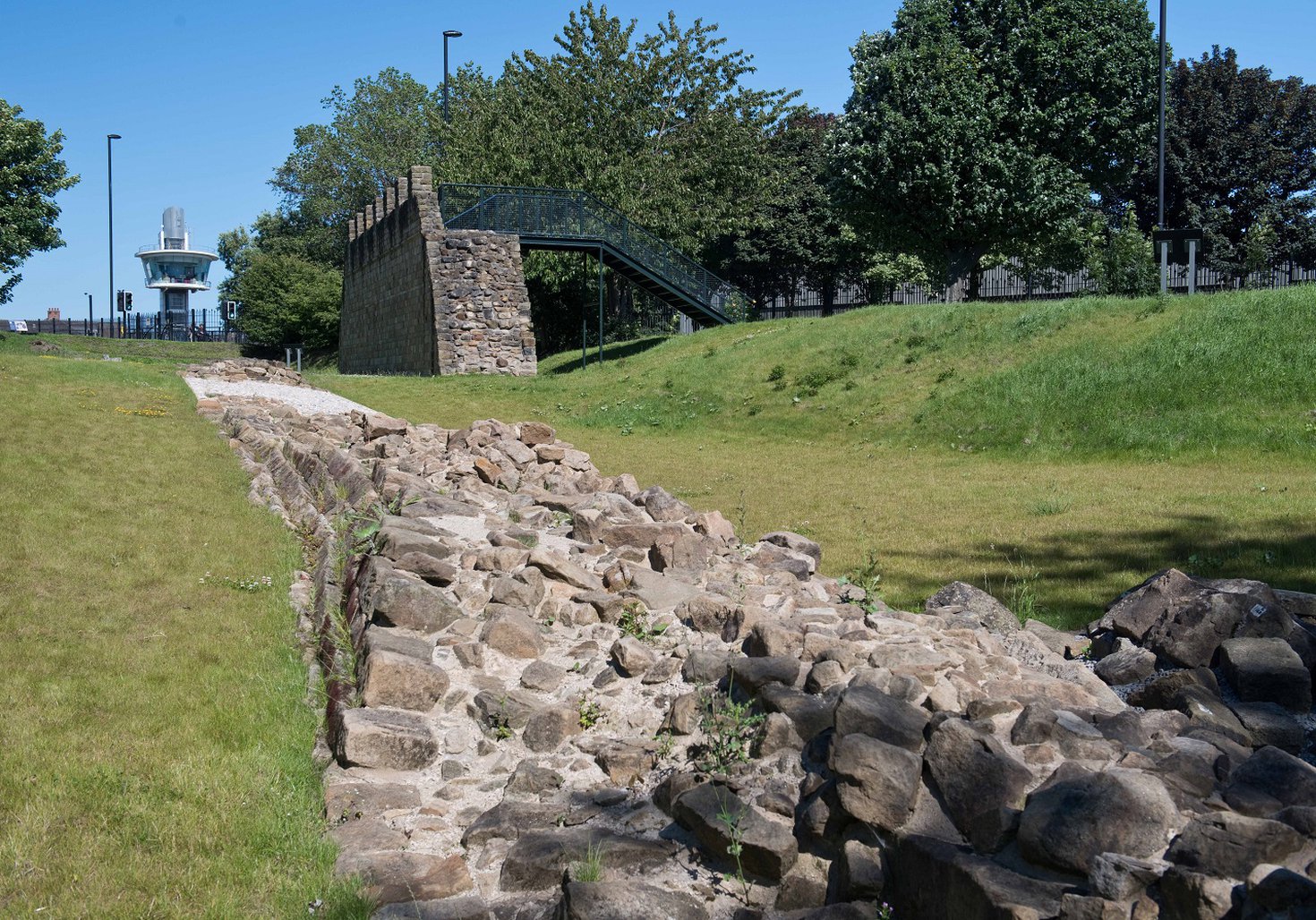 Section of Hadrian's Wall at ground level with Segedunum's viewing tower in the background