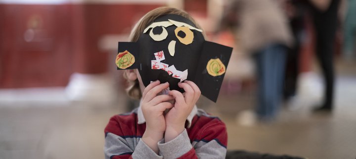 Child hiding behind a Halloween mask