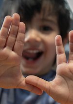 Little smiling boy holds up hands to camera