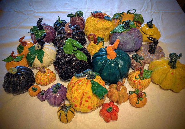A colourful array of painted ceramic pumpkins on a white table cloth.