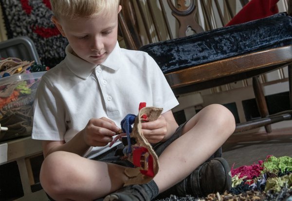 Primary school child making proggy mat