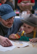 A photograph of a dad helping his young daughter with her arts and crafts.