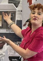 A woman gestures extravagantly to an image of a microwave