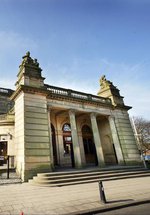 A photograph of the outside of the Shipley Art Gallery. The building is made of a yellow stone with columns in the front.