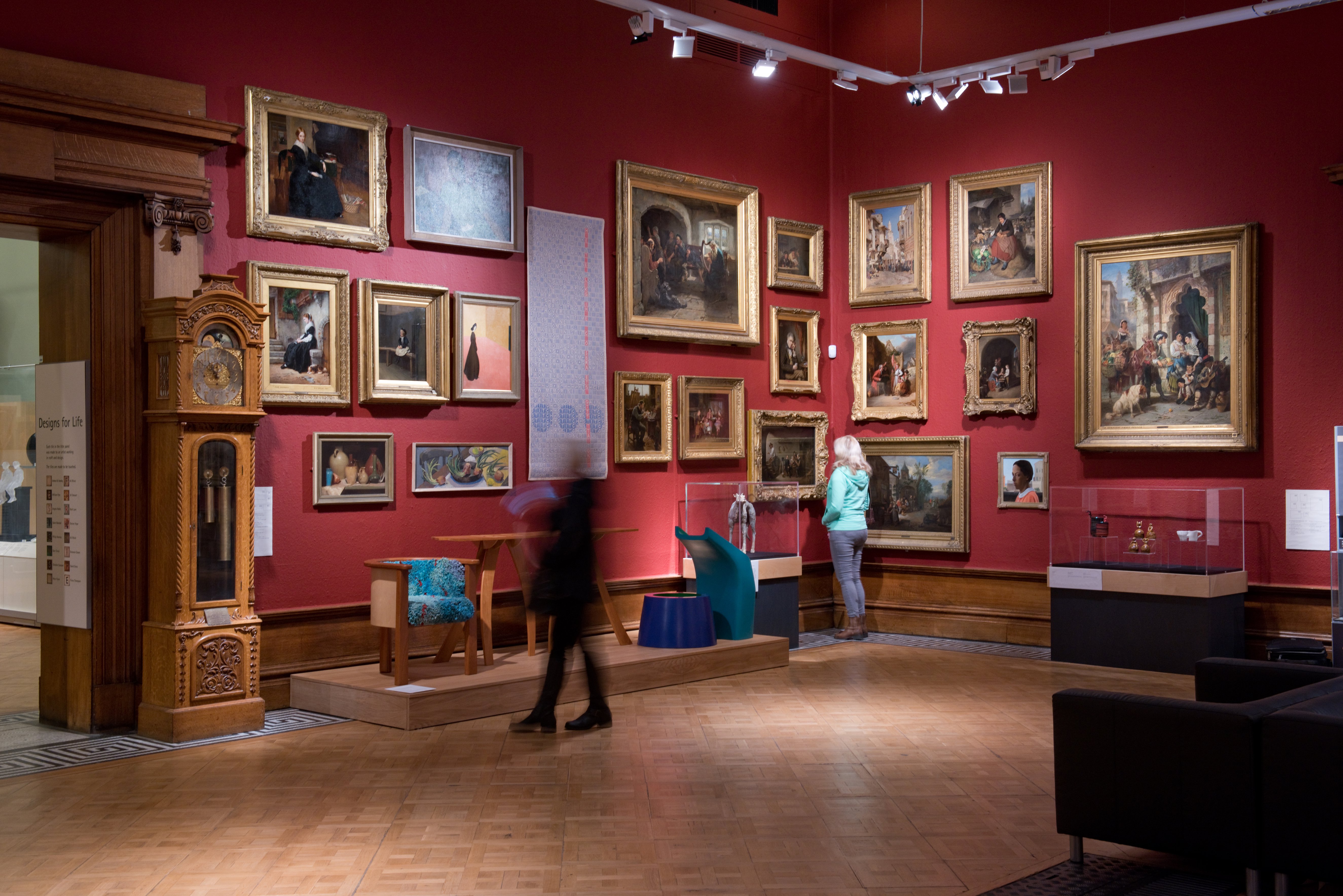 Two people look at the display of paintings on the wall at Shipley Art Gallery Two people look at the display of paintings on the wall at Shipley Art Gallery