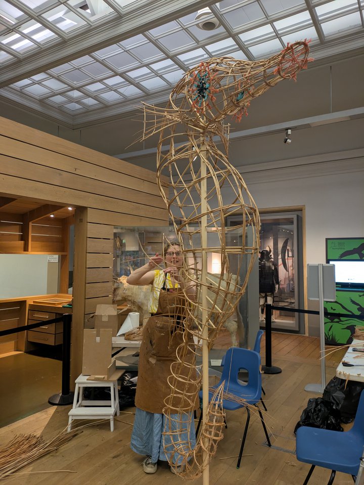 A large seahorse artwork frame is being made by an artist.