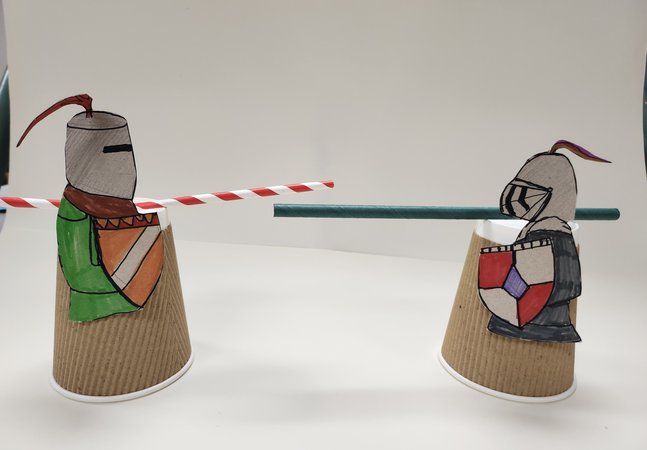 Two knights crafted from paper coffee cups and with straws for swords stand opposite each other ready to joust