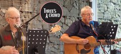 Two men playing guitar and banjo on a stage 