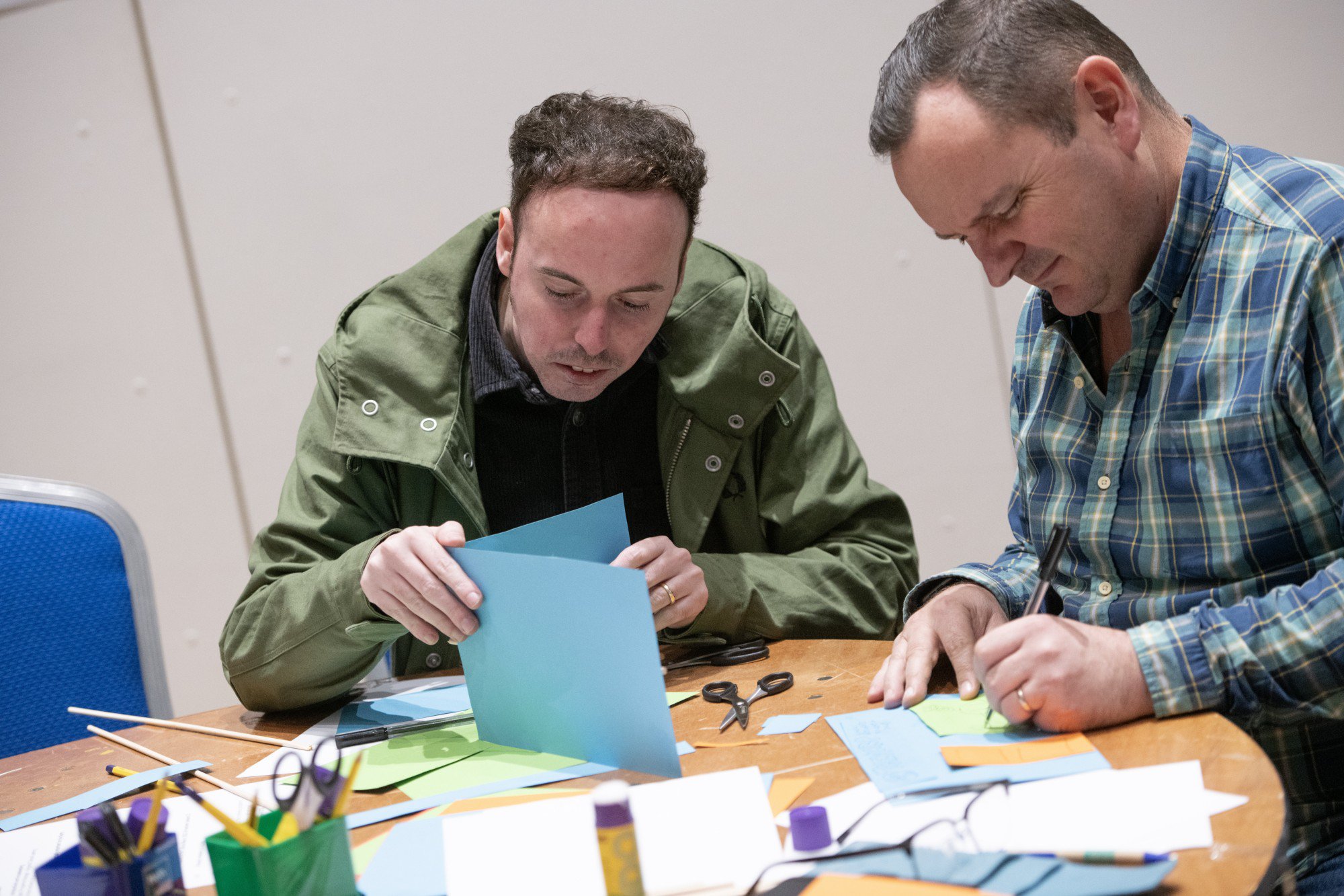 Two people sitting at a table and taking part in a activity together.