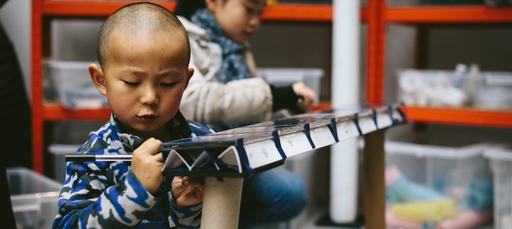 boy creates with cardboard and faintly smiles
