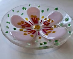 A photograph of a clear glass bowl with a pink flower.