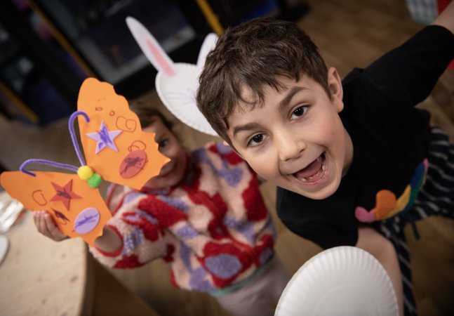 two children hold up their creations and smile