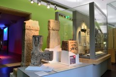 Four Anglo-Saxon carved stone artefacts. One is a fragment of a cross