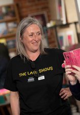 A volunteer in a shop smiling while looking at a guests phone