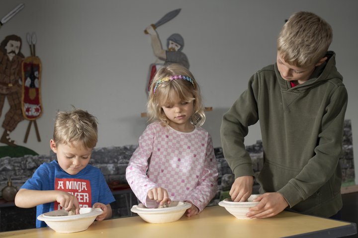 Three children grinding herbs with pestles and mortars