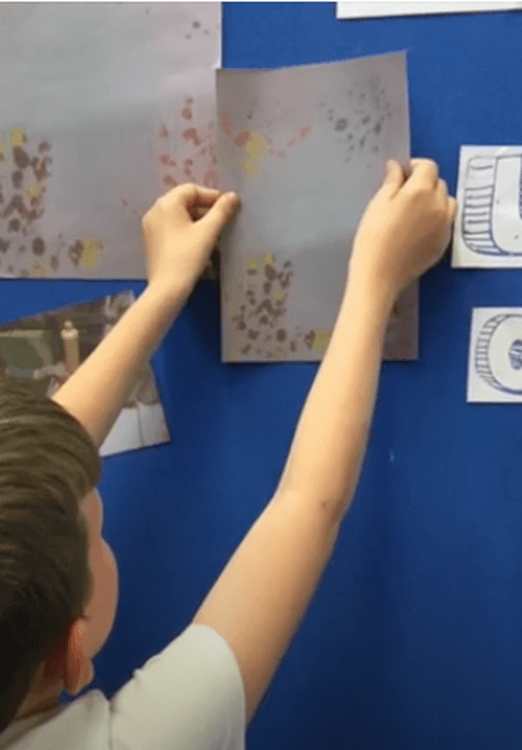 A child sticking artwork to a wall.