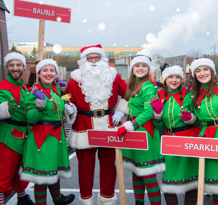 Elves and Santa smiling at the platform at Stephenson Steam Railway