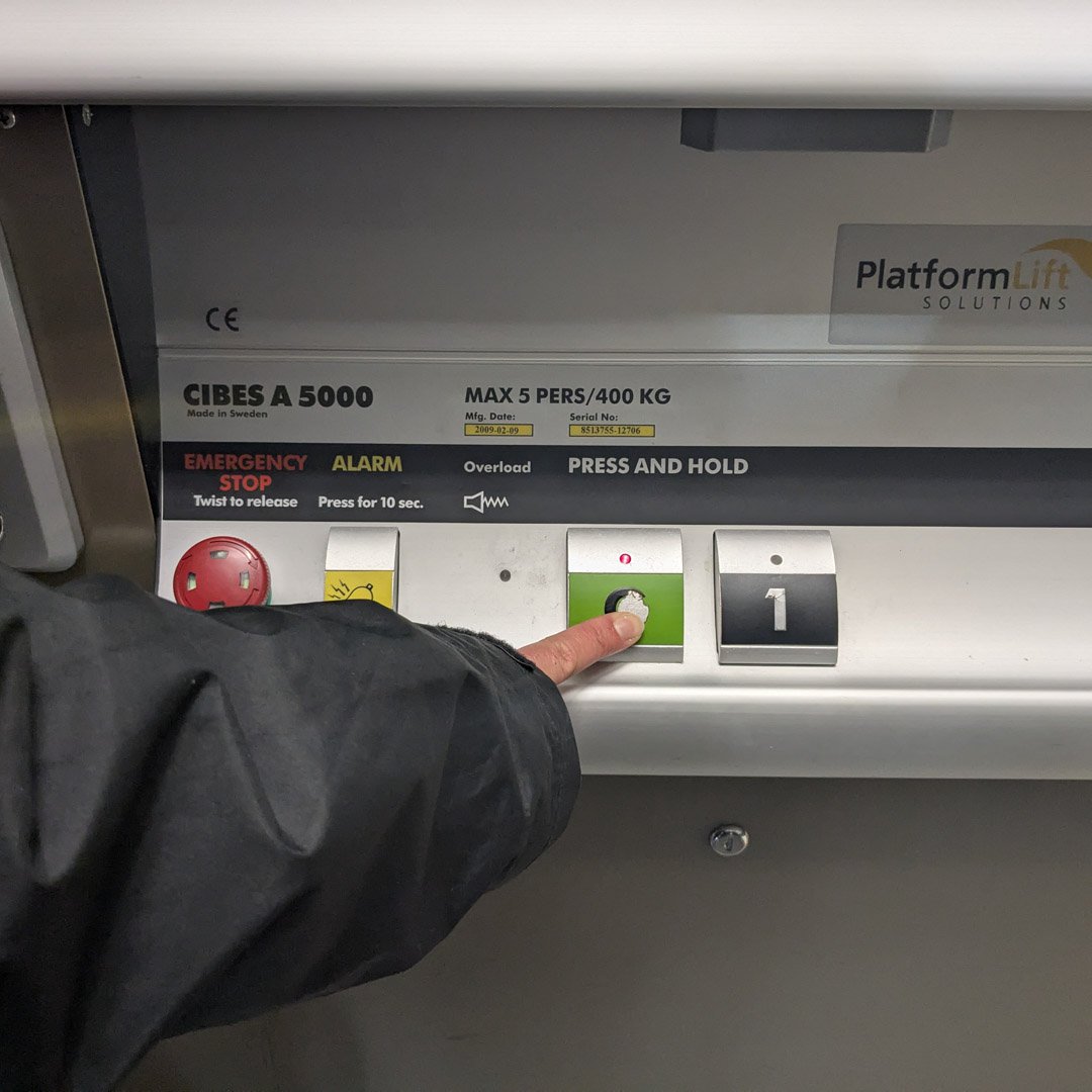 A person pressing their finger on a button in a passenger lift.