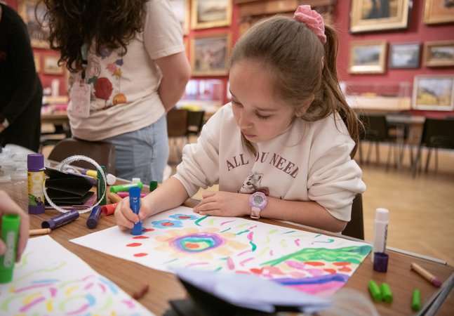 A child sitting and drawing in a large gallery space