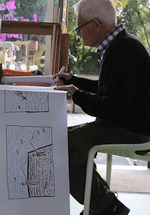 A man is creating an artwork on paper.