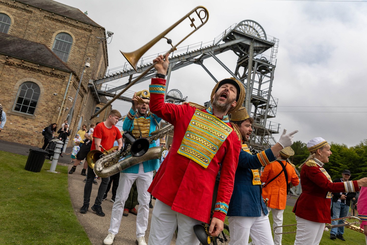 Man in a colourful outfit holding up a trombone.
