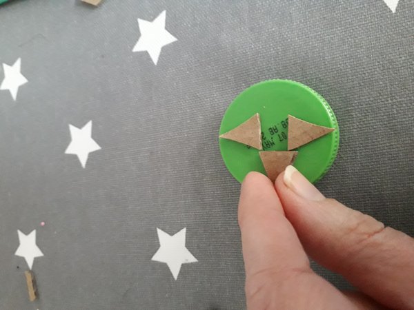 Cardboard shapes stuck to green bottle top