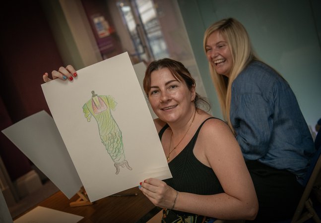 a woman holds up her sketch of a vinatge dress