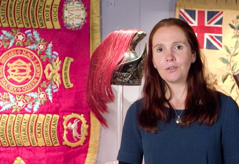 Woman stand s in front of regimental flag talking