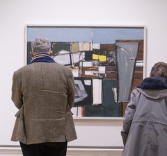 Two people are looking at at abstract painting. 