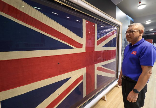 a staff member in blue t-shirt looks at the Trafalgar Flag