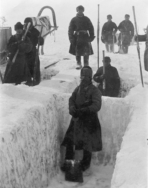 Men standing in holes dug out in ice