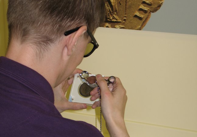 Back view of someone using a loupe to examine an object