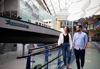Two young adults walk alongside Turbinia