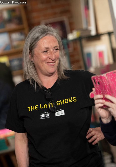 A volunteer in a shop smiling while looking at a guests phone