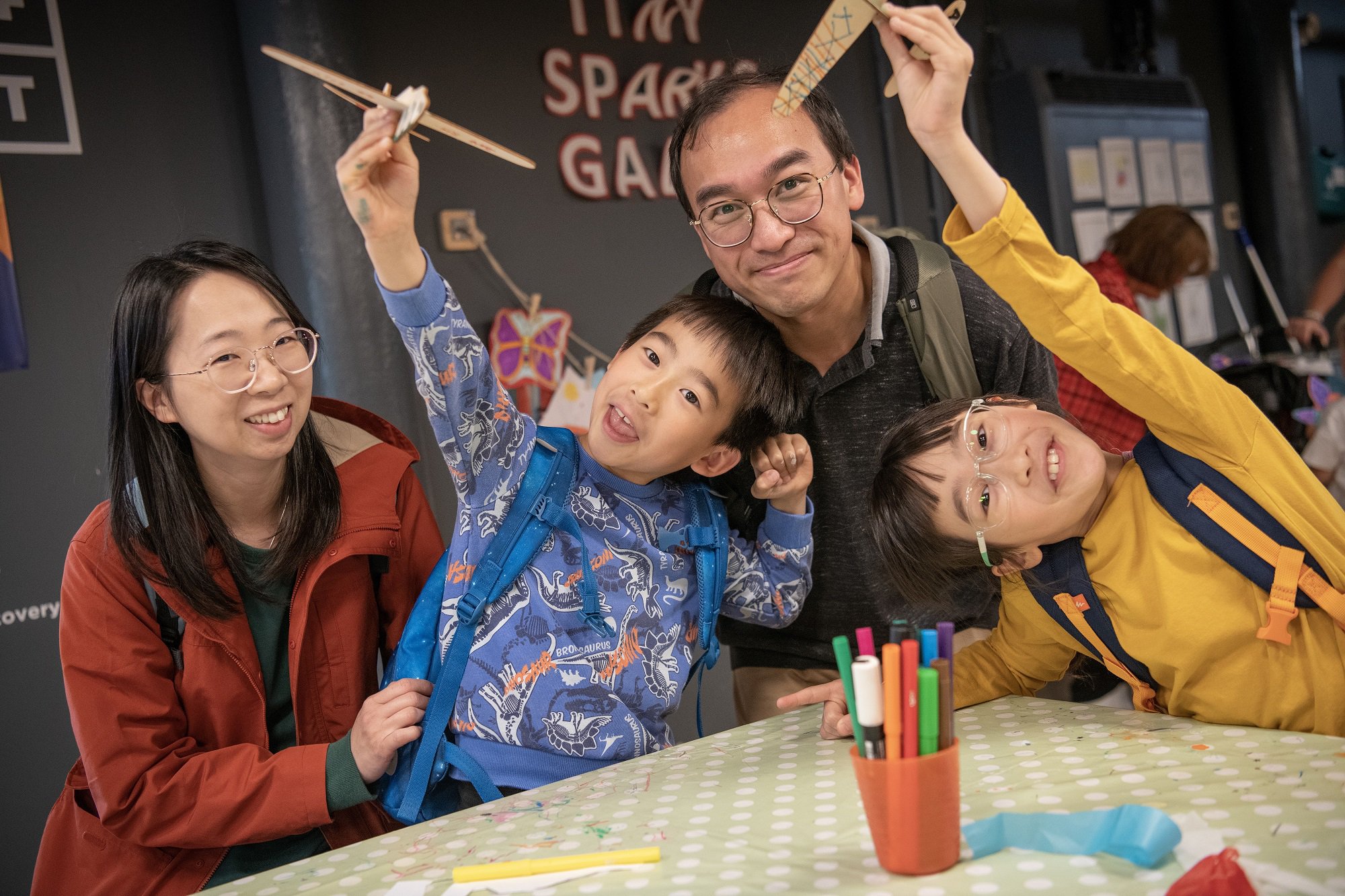 A family of four enjoying a craft activity in a museum.