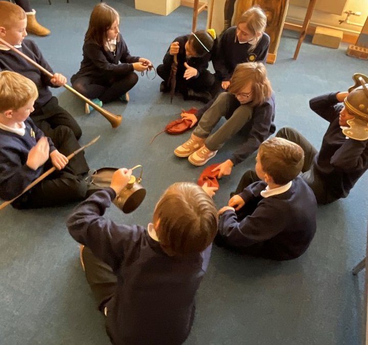 Group of young children sitting on the floor handling historical items