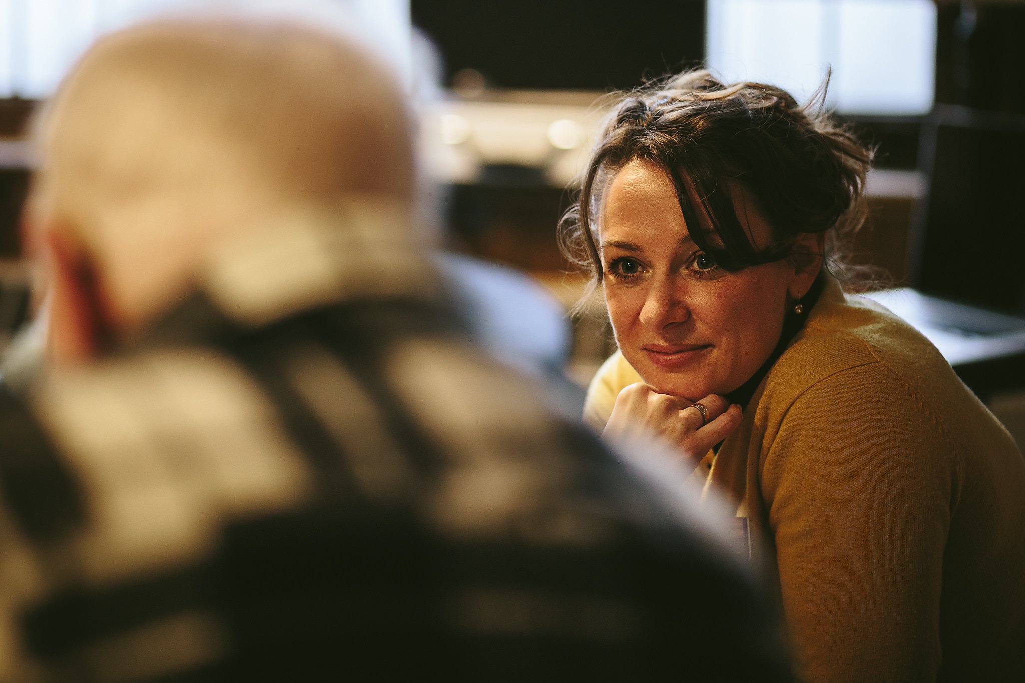 A woman looking on as a group discussion takes place.