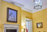 A painting of the building of the Tyne Bridge hangs above a fireplace. The walls are yellow and the ceiling is white.