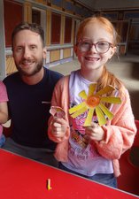 Two young girls with their dad holding the flowers they've made from egg boxes