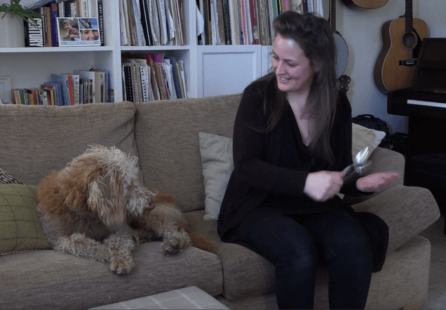 A photo of a woman sitting on a sofa looking at her dog