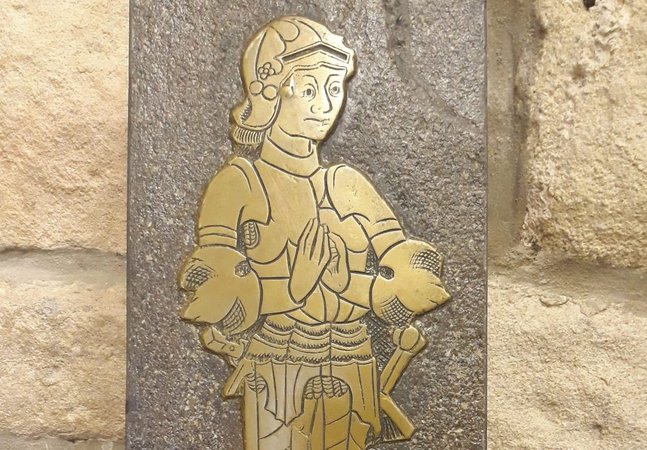 A gold plaque of a character dressed in armour on a brick wall 