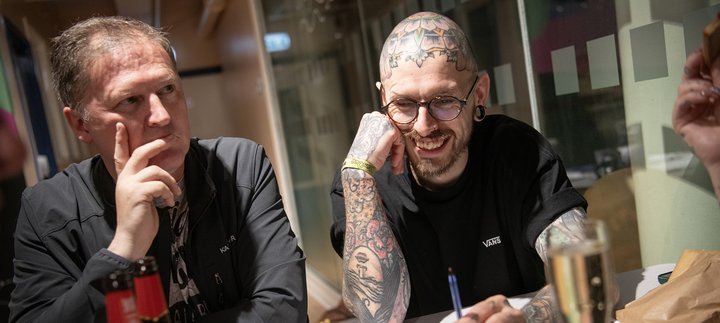 two men sit a table playing a quiz, laughing