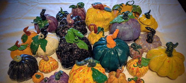 A colourful array of painted ceramic pumpkins on a white table cloth.