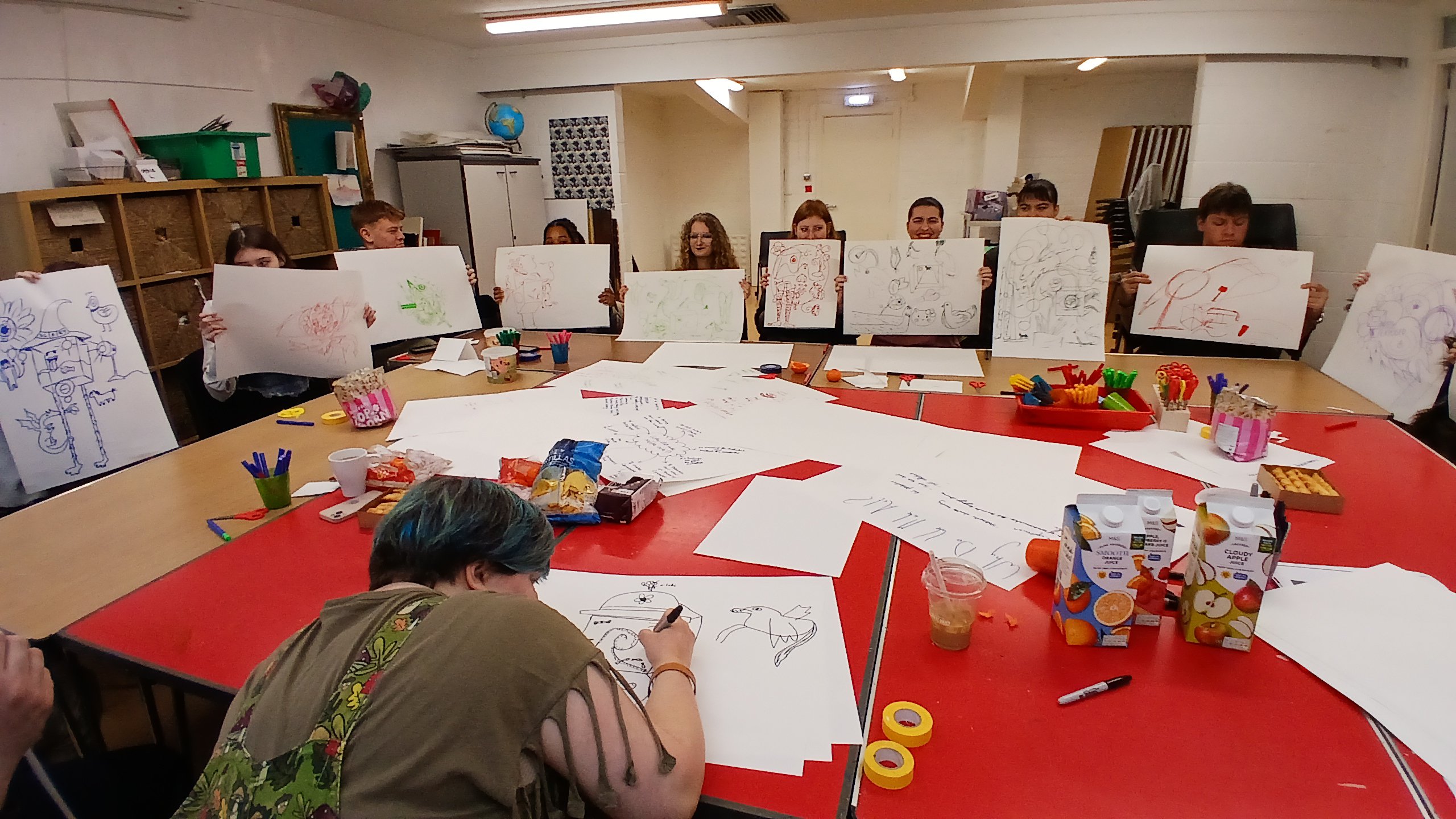 L-INK, a group of young people, are holding up artwork.