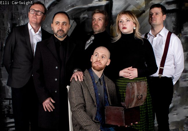 One person sitting down with five people stood up behind him.