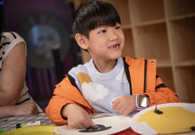 cheeky smiling boy doing craft