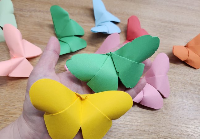 A selection of paper butterflys in coloured paper lying on a table 