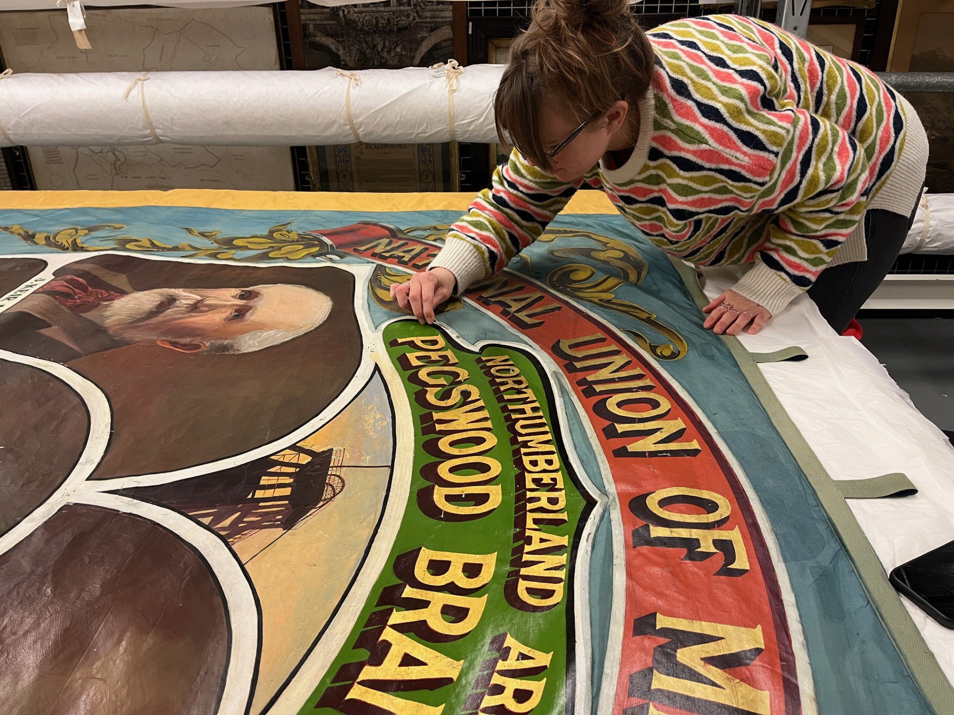 A person conserving a hand painted mining banner. A person conserving a hand painted mining banner.