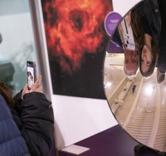 An adult and young person are taking a photo in a concave mirror